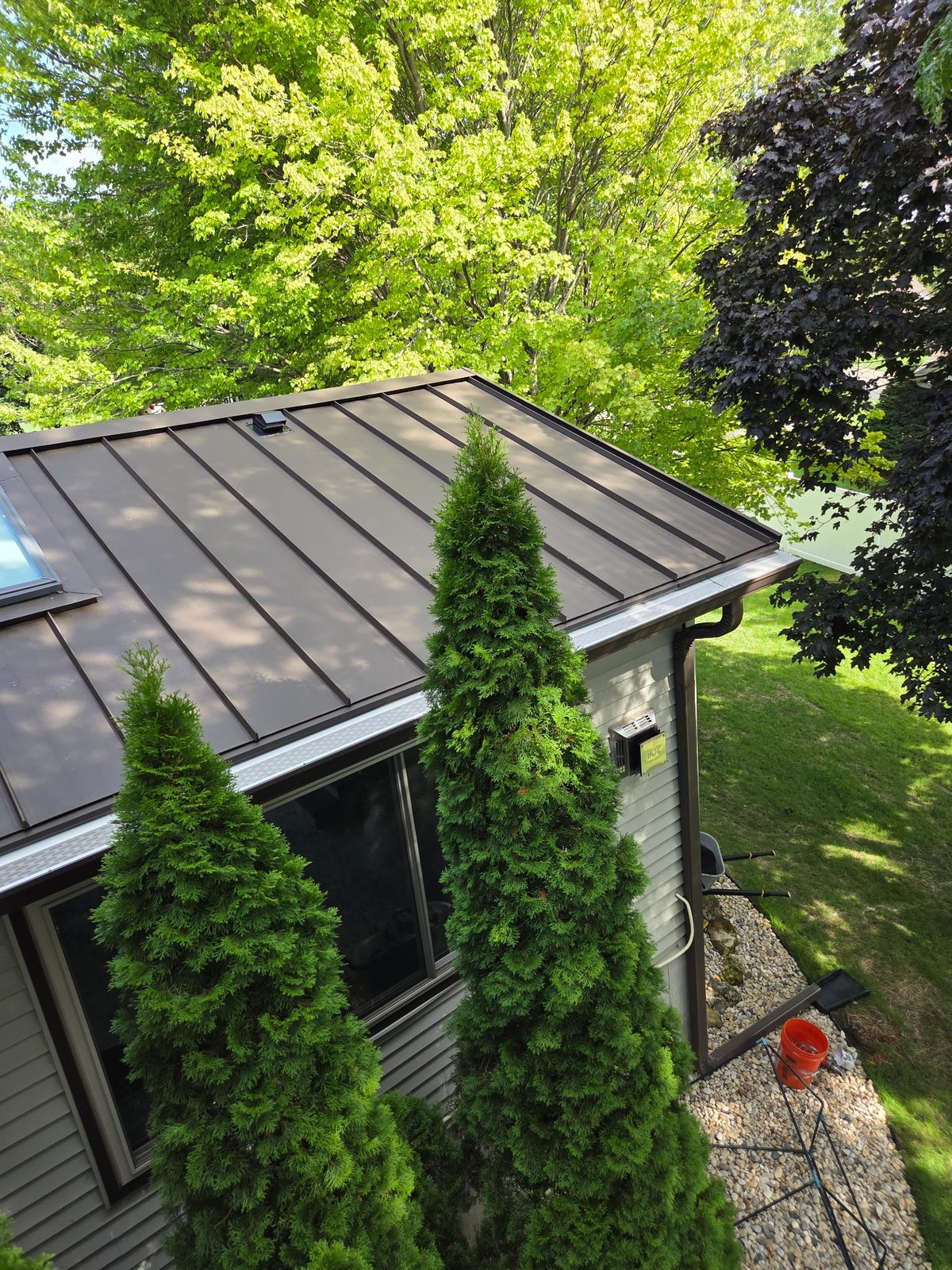Micro-mesh gutter guards installed along a standing-seam metal roof with a skylight