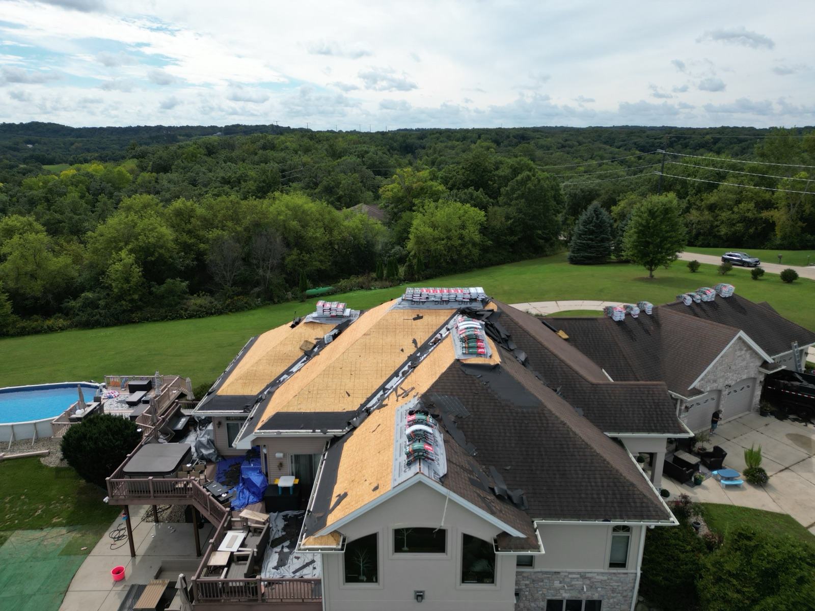 Drone view of the referral roof decked and staged for shingles, pool in the yard below