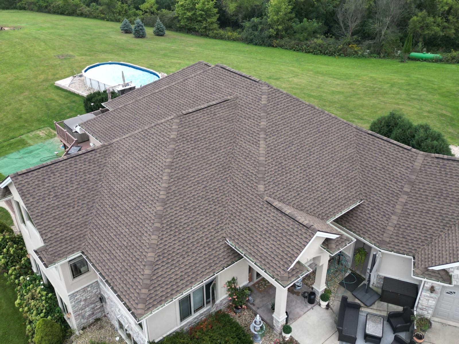 Drone view: finished architectural shingle roof across every slope of the ranch home