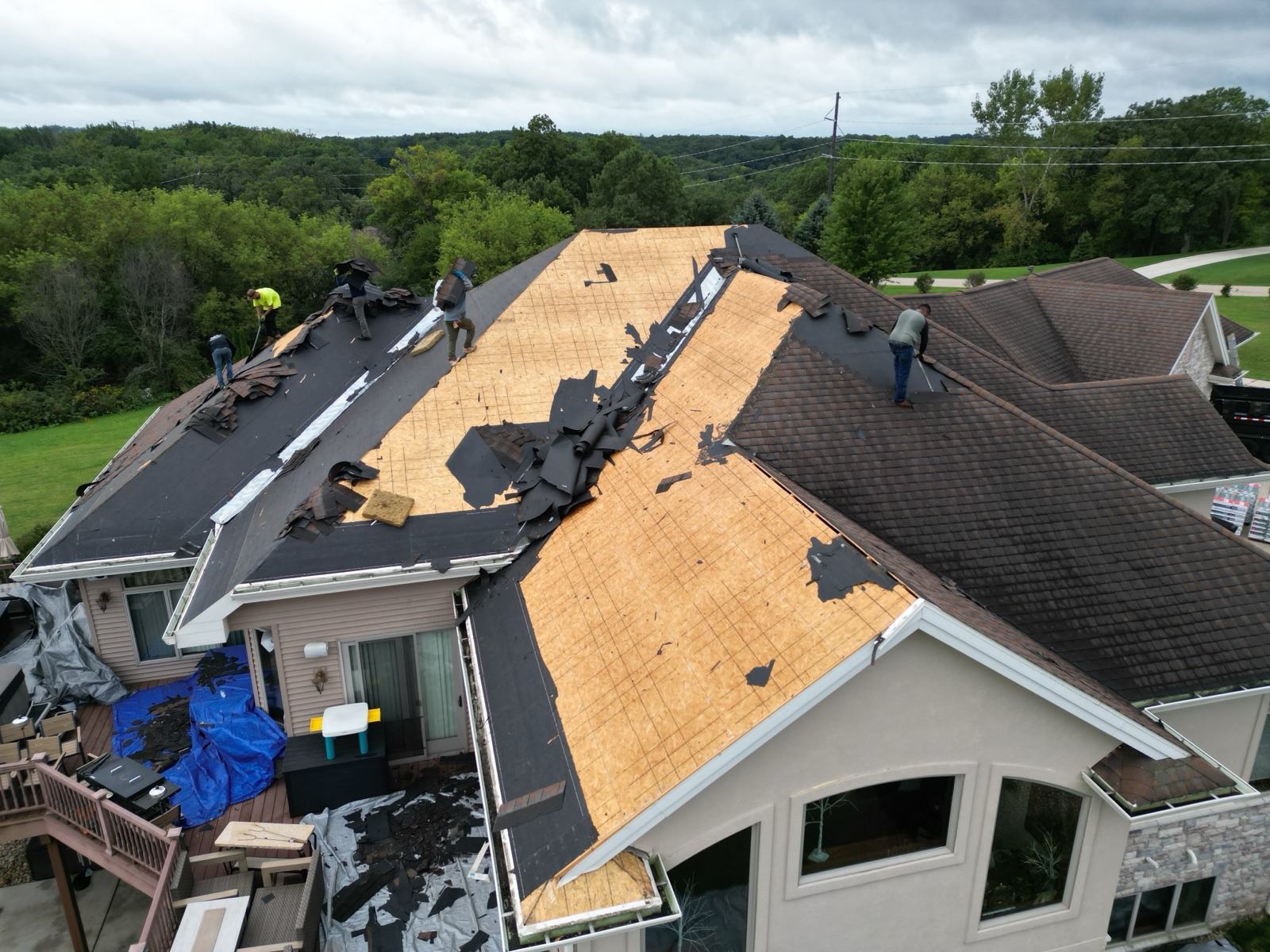 Drone view of the referral roof tear-off in progress, half the shingles stripped